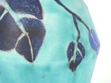 a blue vase with leaves on it sitting on a table