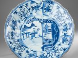 a blue and white plate with a design of a woman in a garden