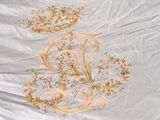 a bed with a white comforter with a floral design on it