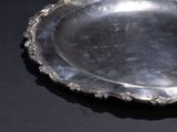 a silver plate on a black table with a black background
