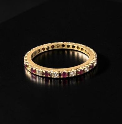 a close up of a gold ring with red stones on a black surface
