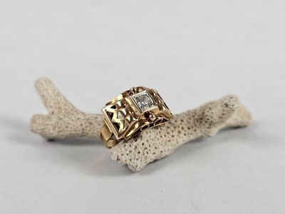 a close up of a gold ring with diamonds on a piece of coral