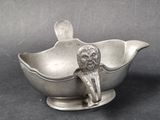 a silver gravy dish with a lion on it