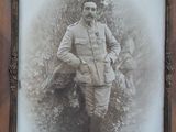 an old photo of a man in a military uniform standing in front of a tree