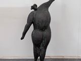 sculpture représentant une femme debout sur un socle, de dos par rapport à la caméra