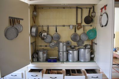 many pots and pans on the shelves in this kitchen