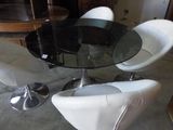 a glass table with four white chairs around it