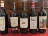 several bottles of wine are lined up on a red table cloth