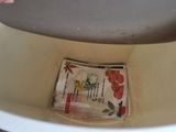 a newspaper in a bowl on the floor of a bathroom