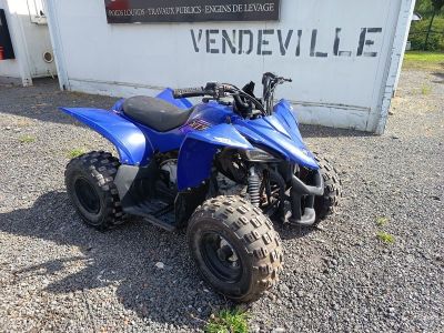 une photo d'un quad bleu garé devant un immeuble