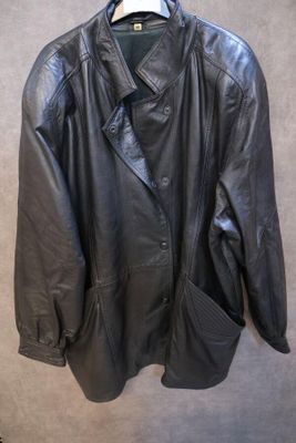 une veste en cuir noir suspendue à un cintre accroché au mur
