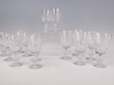 six verres à vin en cristal et une carafe posés sur un plan de travail blanc