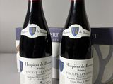 two bottles of red wine sitting next to each other on a table