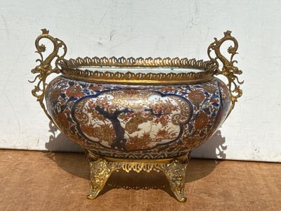 un grand vase à pied doré posé sur une table