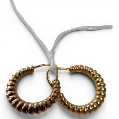 two gold hoop earrings on a white background with a white ribbon