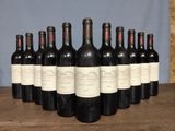 six bottles of red wine lined up on a wooden table