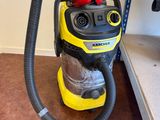 yellow and black vacuum cleaner sitting on the floor next to a shelf