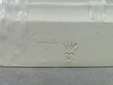 a white vase with a crown on it sitting on a table