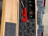 une caisse en bois posée par terre, contenant des outils