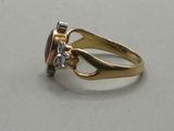 a close up of a gold ring with a red stone and a diamond