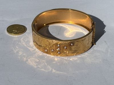 a gold bracelet and a coin sitting on a table