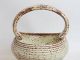 a white bowl with a handle on a white surface