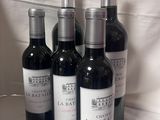 quatre bouteilles de vin sont alignées sur une nappe blanche