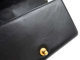 black leather purse with gold hardware on white background