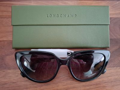 Lunettes de soleil Longchamp noires et blanches, avec un étui vert