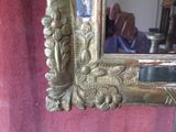 a mirror with a gold frame on a red wall