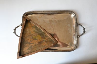 a silver tray with a painting on it on a table