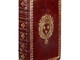 an old red book with gold trimming and ornate design