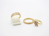 deux bagues en or et une bague sertie d'une pierre rose sur un fond blanc