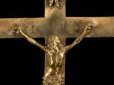 gold crucifix on a black background with a crown above it