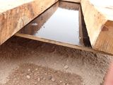 a man standing next to a wooden structure that has a water hole in it