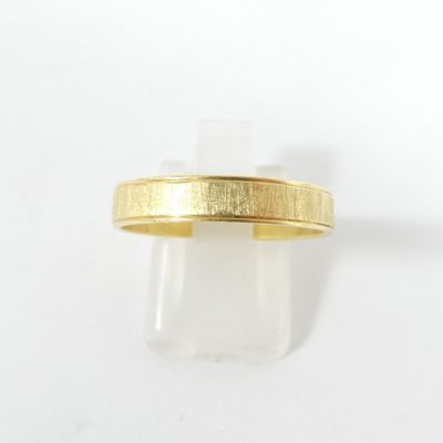 gros plan d'une bague en or sur une surface blanche