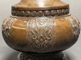 a large metal vase with a handle on a table
