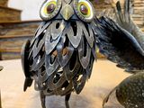 sculpture of an owl made out of scrap metal sitting on top of a table