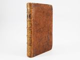 an old book with a brown cover sitting on top of a white surface