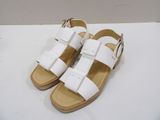 the white sandals are on a white surface with a white wall in the background