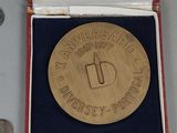une médaille d'or dans une boîte rouge, à côté d'une paire de ciseaux