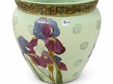 a green vase with purple flowers on it on a white surface