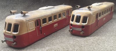 two toy trains sitting side by side on the ground