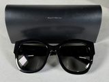 des lunettes de soleil à monture noire, accompagnées d'un étui noir, posées sur une surface blanche