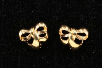 two pairs of gold tone bow earrings on a black background