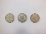 three different british coins sitting on top of a white surface