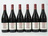 six bouteilles de vin rouge sont alignées sur une surface blanche