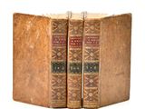 two old books sitting on top of each other on a white surface