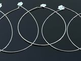 four pairs of silver hoop earrings sitting on top of a black surface