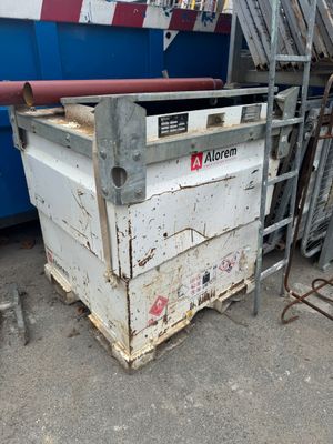a dumpster that is sitting in front of a blue dumpster